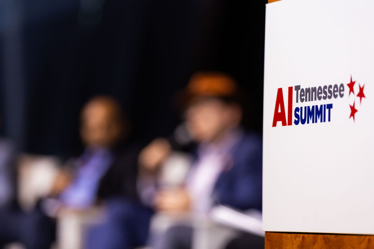 Participants engage in discussions at the AI Tennessee Summit, as the event's logo is prominently displayed in the foreground.